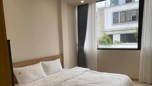 Una habitación de hotel con cama, ventana con cortinas y vista a un edificio.