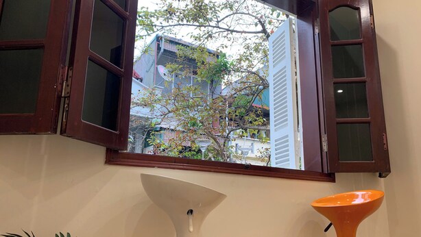 Una habitación con ventana, una lámpara de pie blanca y una lámpara cónica naranja.