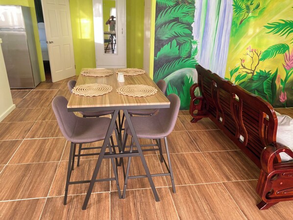A dining area with a wooden table, four chairs, and a bench. - 1-bedroom condo in charming Choiseul with AC, WiFi. Book now (Castries)
