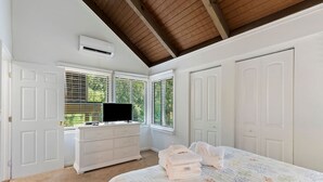 A bedroom with a bed, a dresser, a television, and a window with blinds.