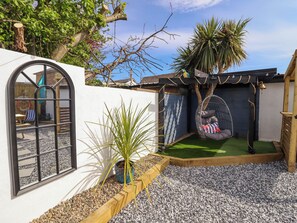 Un cortile accogliente con un'amaca, un piccolo giardino e un patio in legno.