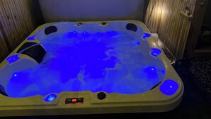 A hot tub with a control panel and a wooden wall in the background.