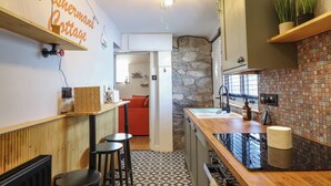 A compact kitchen with a stone wall, a wooden countertop, and a tiled backsplash.