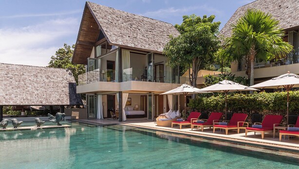 Un resort con piscina, tumbonas y un edificio de dos pisos con balcones.