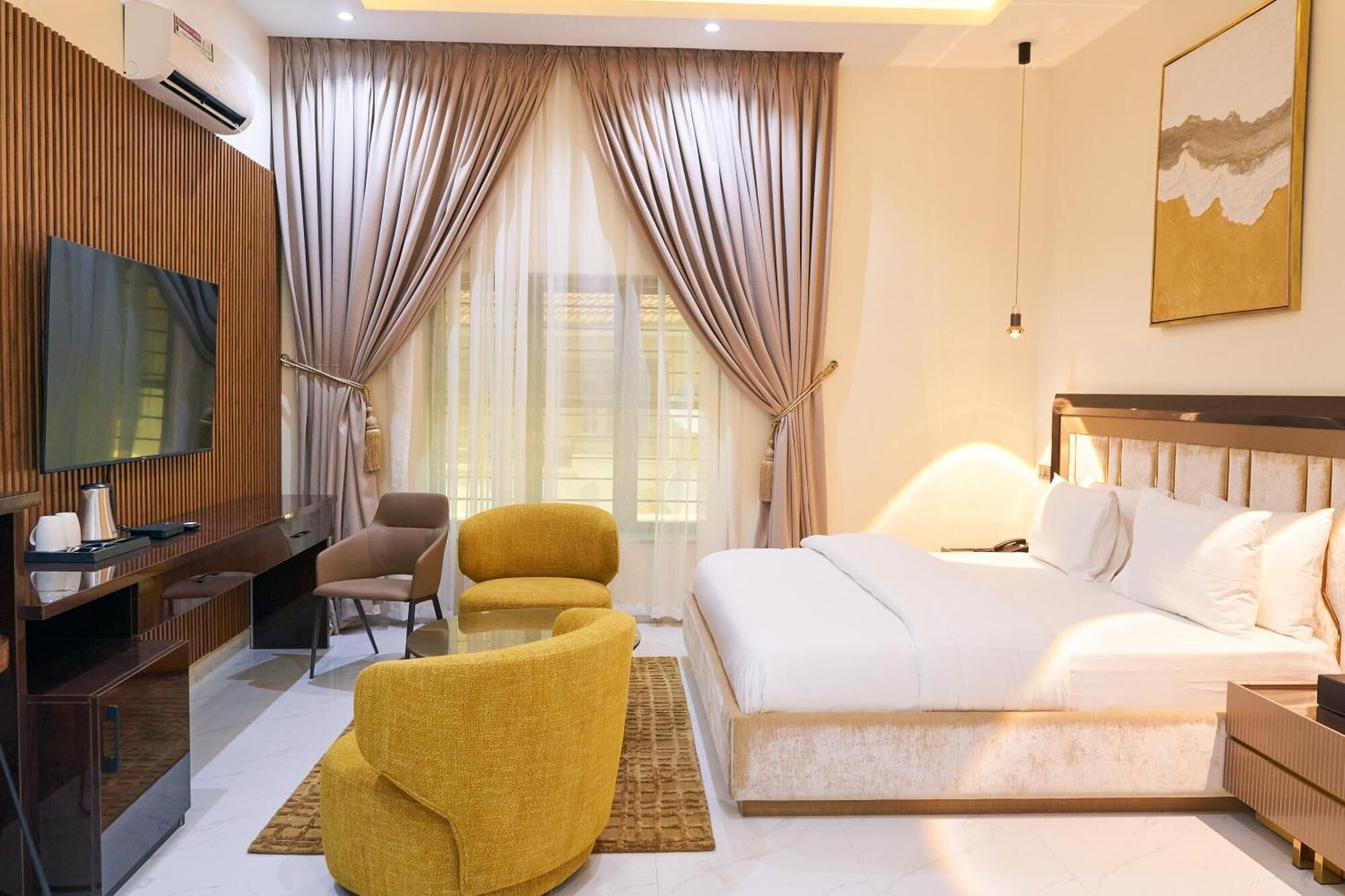 Une chambre d’hôtel comprenant un lit, un bureau avec une chaise, un canapé, une télévision et un tableau au mur.