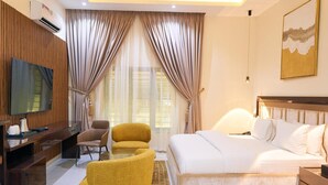 Une chambre d’hôtel comprenant un lit, un bureau avec une chaise, un canapé, une télévision et un tableau au mur.
