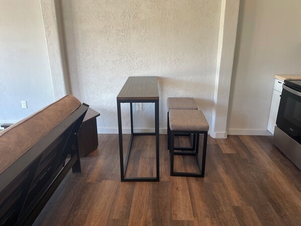 Une cuisine moderne avec un banc en bois, une table accompagnée de deux tabourets rembourrés et un four encastré.
