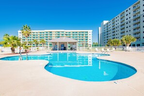 A hotel with a swimming pool, a covered area, and a large building with multiple balconies. - Beachfront  - Fantastic Beach Vacation for Family Fun (Gulf Shores)