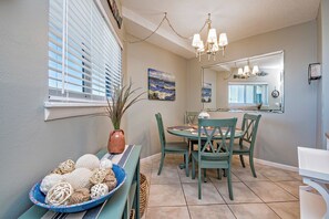 A dining area with a round table, green chairs, and a blue bowl of decorative items. - Beachfront  - Fantastic Beach Vacation for Family Fun (Gulf Shores)