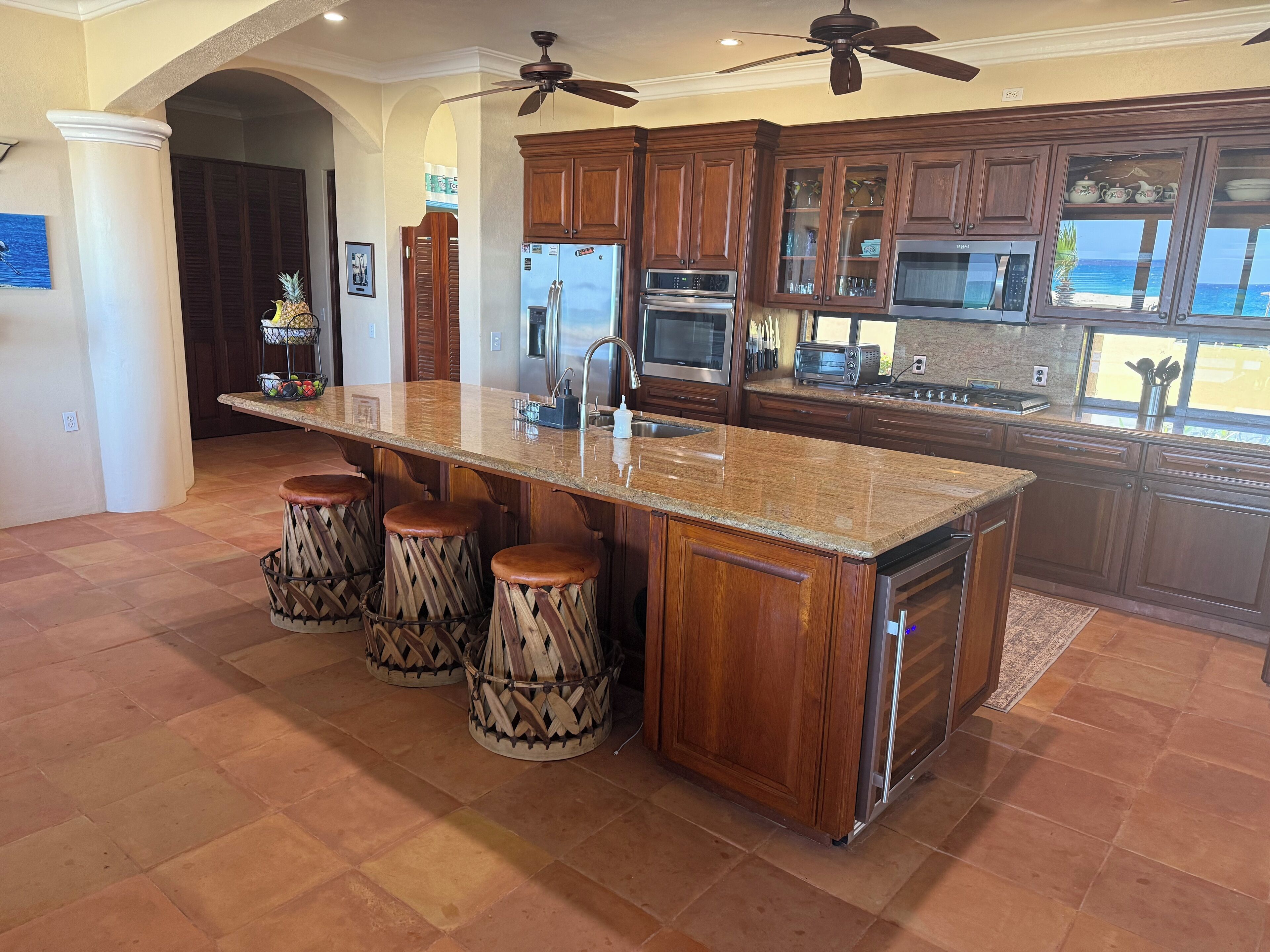 A kitchen with a central island, wooden cabinets, and a view of the ocean.