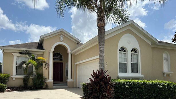 A two-story house with a beige facade, a red door, and a garage.