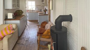 En hyggelig stue med en sofa, en lænestol og en sort ovn.