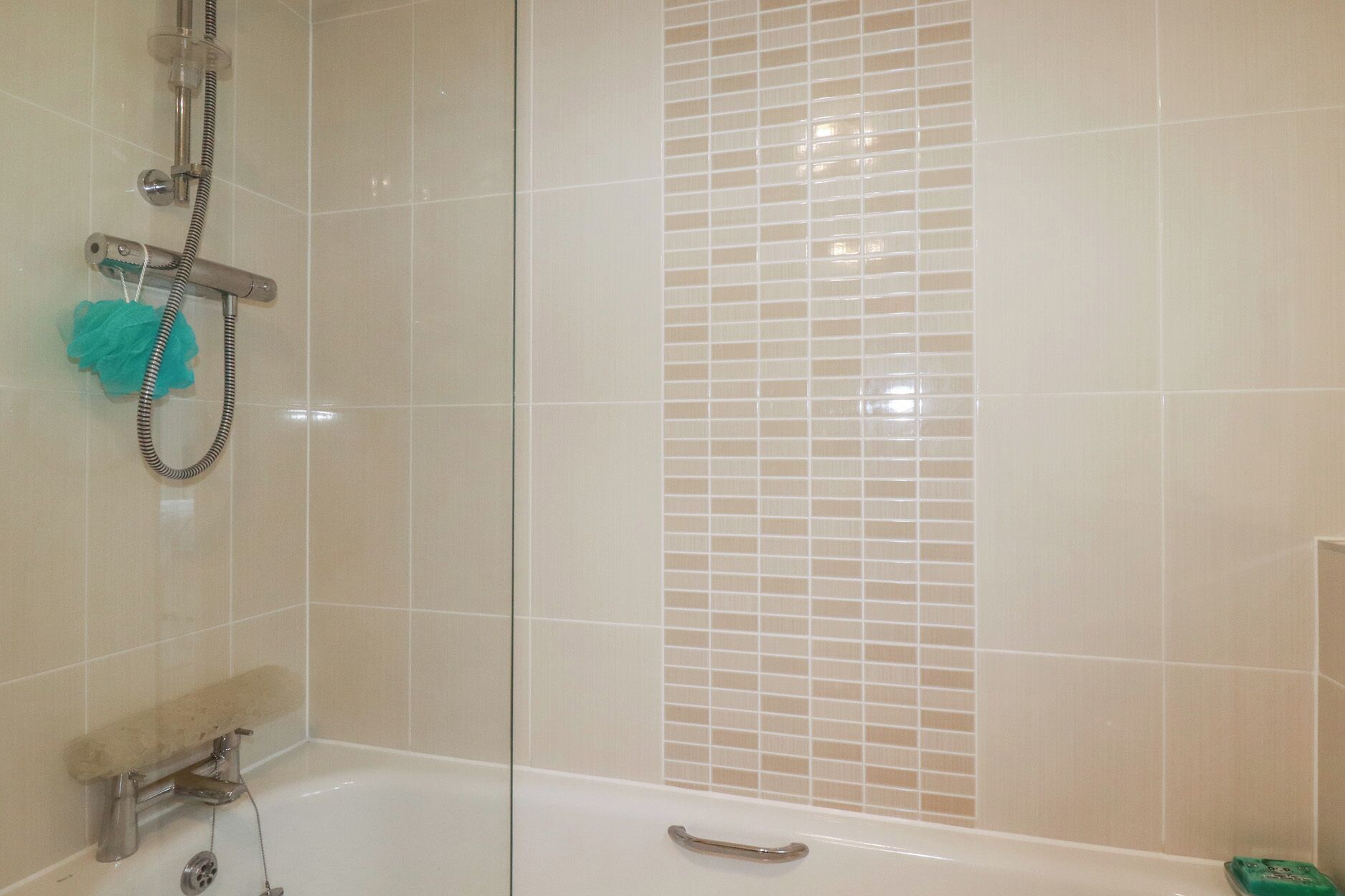 A bathroom with a bathtub, a shower, and a tiled wall.