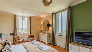 Une chambre d’hôtel avec un lit, un bureau, une chaise, une télévision et une fenêtre donnant sur un beau paysage.