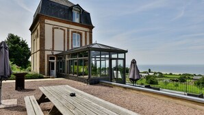 Un bâtiment doté d’une véranda en verre donnant sur une plage.
