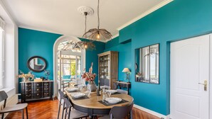 Une salle à manger avec une table ronde dressée pour six personnes, un buffet en bois et un grand miroir au mur.