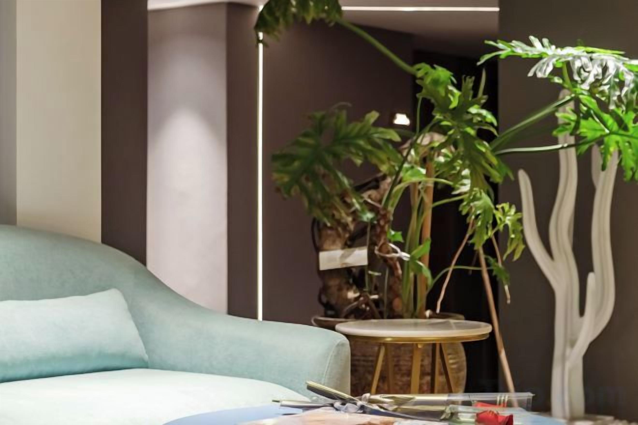 A room with a light blue sofa, a round wooden table, and a potted plant.