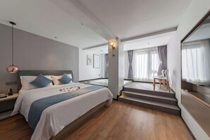 A modern hotel room with a large bed, a desk, and a view of the city. - Allston Hotel (Xiamen)