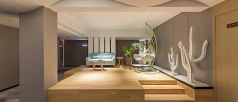 Un vestíbulo moderno con plataforma de madera, zona de estar y arte abstracto en la pared.