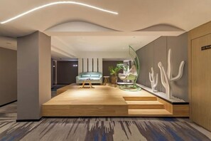 Eine moderne Lobby mit einer Holzplattform, einer Sitzecke und abstrakter Wandkunst.