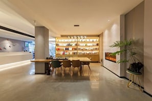 A modern interior with a reception desk, a seating area, and a display of items on shelves. - Allston Hotel (Xiamen)