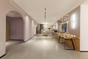 Ein moderner Hotelgang mit Essbereich, einer Rezeption und einem großen Fenster.