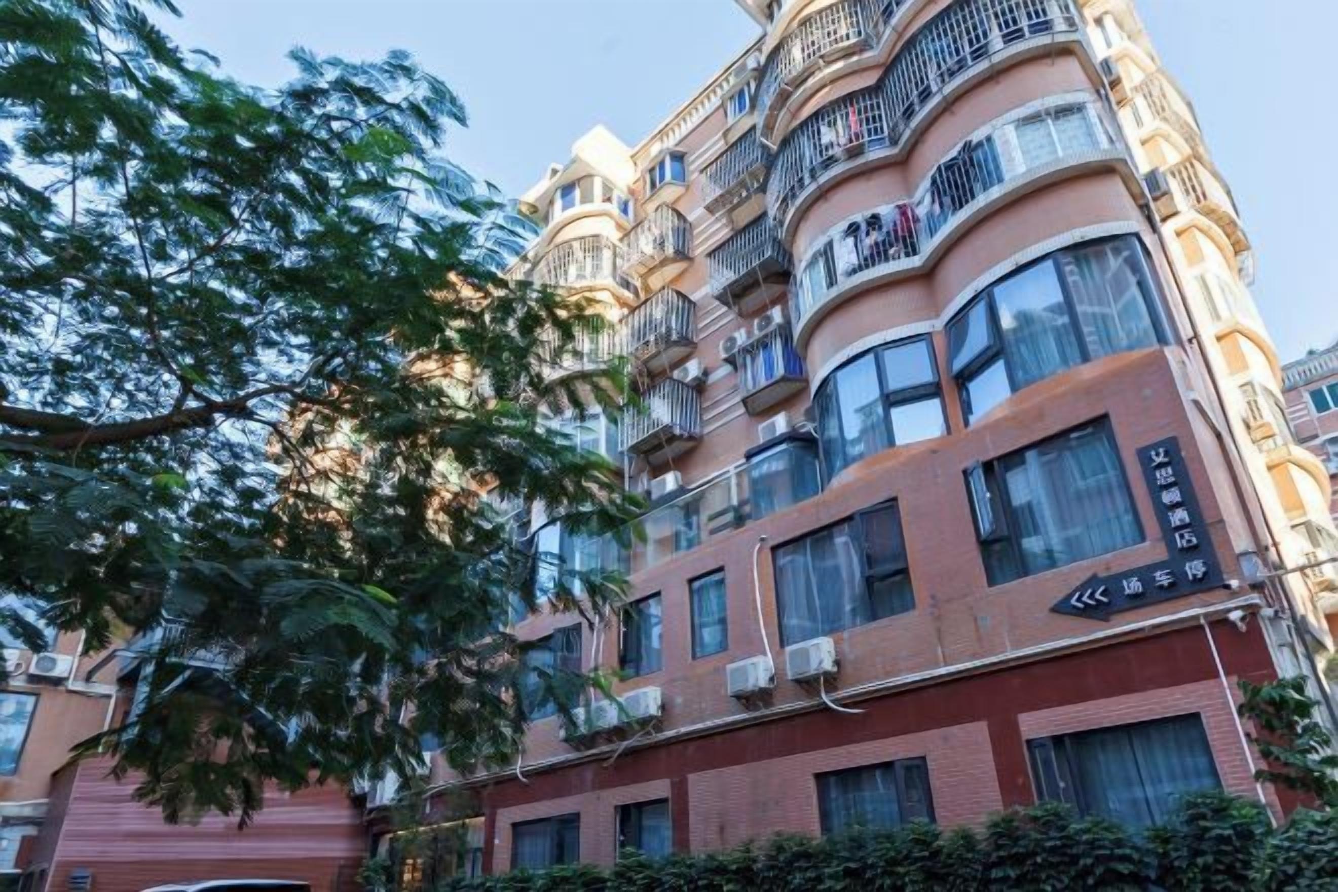 A multi-story building with balconies, large windows, and signage indicating a hotel.