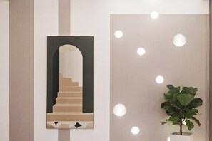 A wall with a framed architectural drawing of a staircase, a potted plant, and recessed lighting. - Allston Hotel (Xiamen)