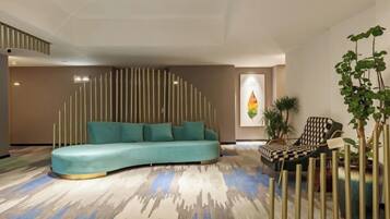 A modern living room with a curved sofa, a patterned carpet, and a decorative wall.