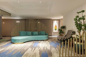 A modern living room with a curved sofa, a patterned carpet, and a decorative wall. - Allston Hotel (Xiamen)