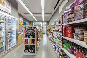 A grocery store aisle with refrigerated sections on the left and shelves stocked with various products on the right. - Allston Hotel (Xiamen)