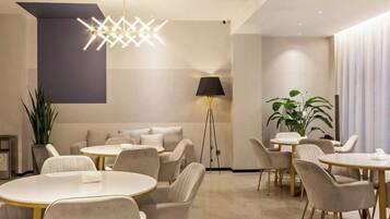 A modern dining area with round tables and chairs, a floor lamp, and a potted plant.