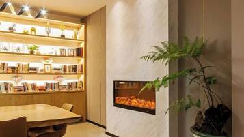 A room with a wooden bookshelf, a dining table, and a fireplace.