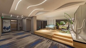 A modern lobby with a wooden platform, a sofa, and a chair. - Allston Hotel (Xiamen)