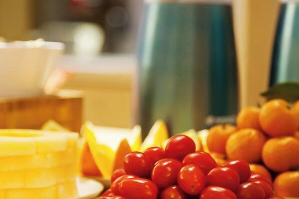 A table with a variety of fruits including oranges and tomatoes.
