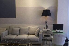 A modern living room with a sofa, a small table with a lamp, and a chair. - Allston Hotel (Xiamen)