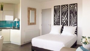 Et moderne hotelværelse med seng, lille rundt bord, sofa og dekorativ vægpanel.