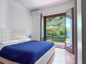 Ein Schlafzimmer mit Bett, Fenster und Blick ins Freie.