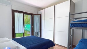 Ein Schlafzimmer mit einem Bett, einem Schlafkoje und einem Fenster mit Vorhängen sowie einem Heizkörper.
