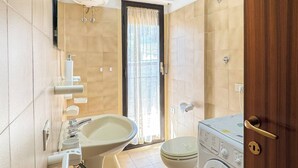 A bathroom with a toilet, sink, and washing machine.