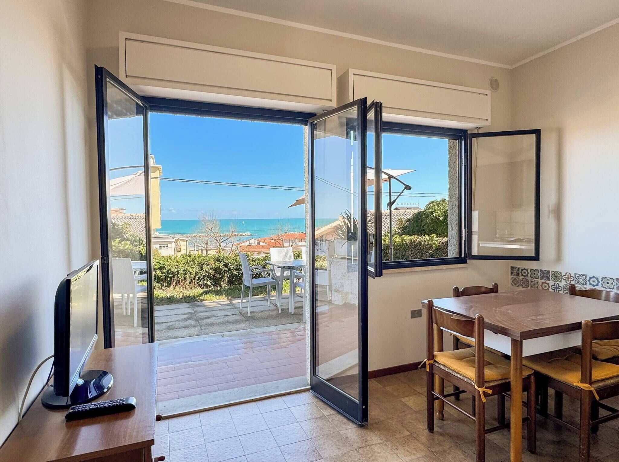 Una habitación con puerta de cristal corredera que da a un balcón con vista al mar.