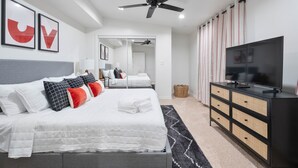 A modern bedroom with a bed, a TV, a ceiling fan, and a dresser. - Ultimate Tech Home - Ready for Football Season! (Lubbock)