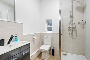A modern bathroom with a toilet, sink, and shower. - 5 Guests - 2 Bedrooms - Brighton Centre - Petsok (Brighton)
