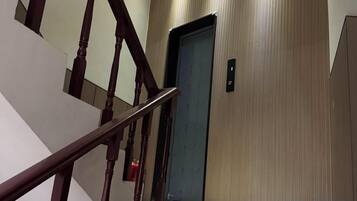 A staircase with wooden handrails leading to an elevator.