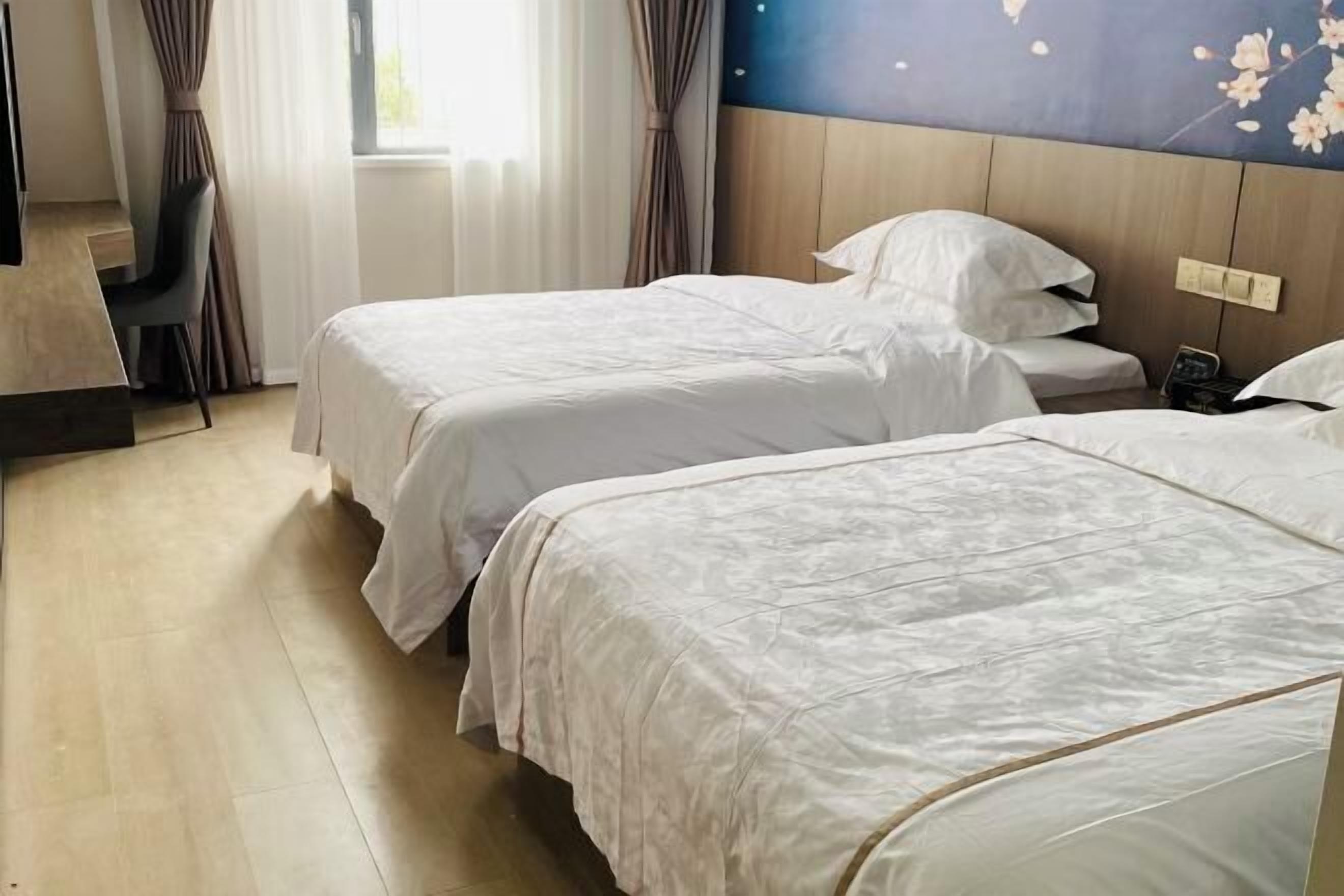 A hotel room with two beds, a desk, and a chair.