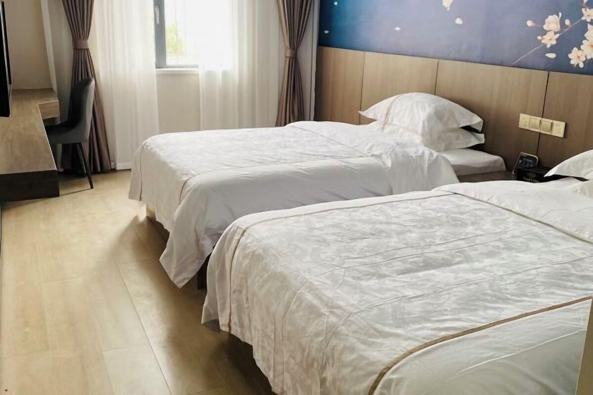 Une chambre d’hôtel avec deux lits, un bureau et une chaise.