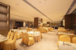 Un salón de banquetes con mesas redondas, sillas amarillas y un pilar central.