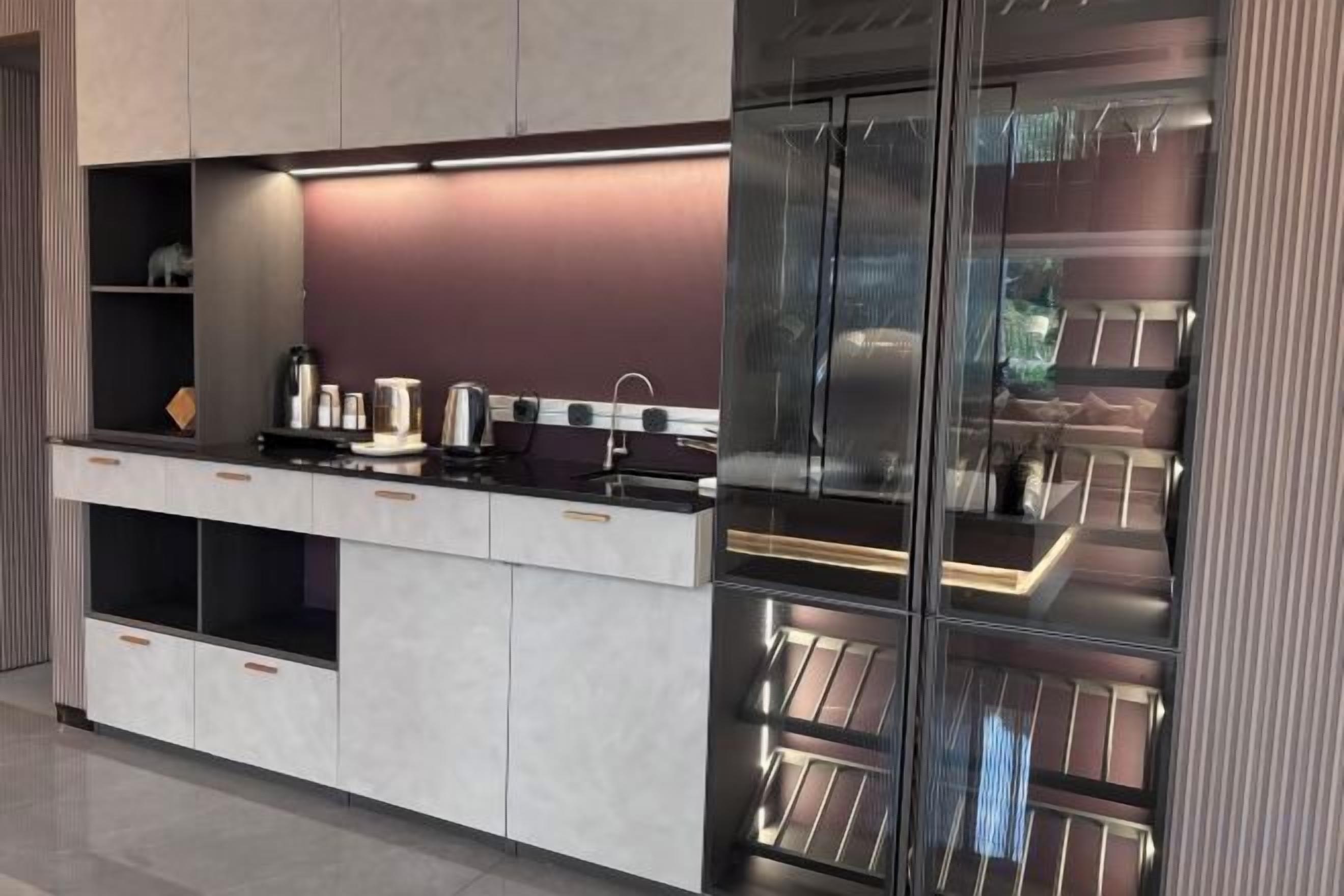 A modern kitchen with built-in appliances, a countertop, and a glass-fronted pantry.