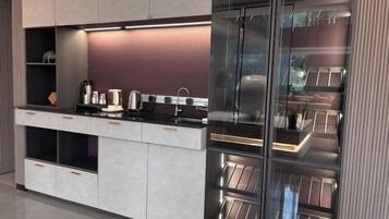 A modern kitchen with built-in appliances, a countertop, and a glass-fronted pantry.