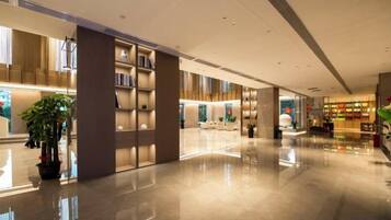 A spacious lobby with a polished floor, a bookshelf, and a seating area.